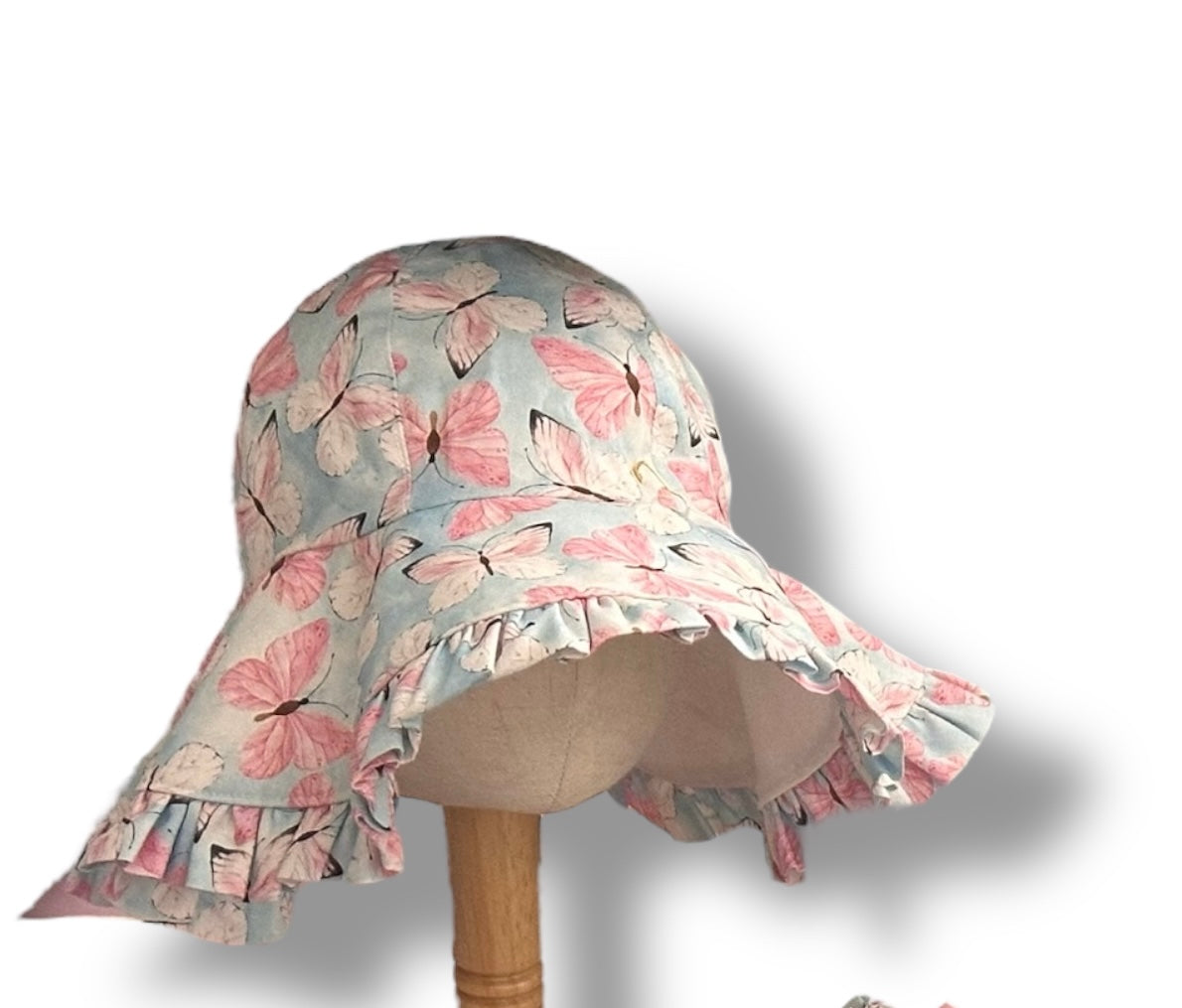 Handmade children's sunhat in baby blue with pink and white butterfly print, on a mannequin stand with a white background.