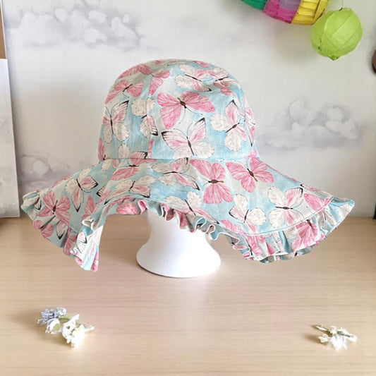 Handmade children's sunhat in baby blue with pink and white butterfly print, on a white stand with a light background.
