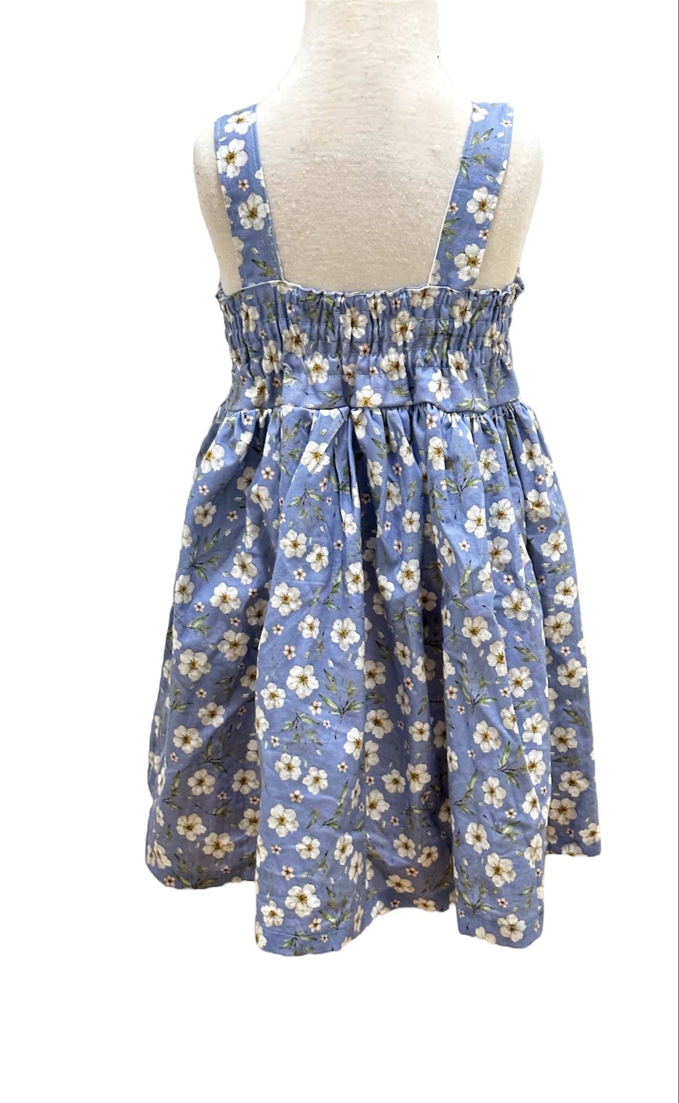 The back of a blue floral summer dress with an elasticised back on a mannequin.