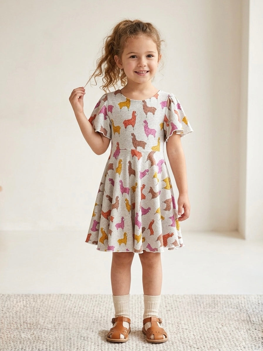 Young girl wearing a dress with llama pattern on a plain background