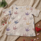 Gender-neutral children’s graphic T-shirt featuring an inclusive hand-sign design on a soft neutral cotton tee