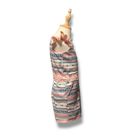 A side view of a handmade romper with a whimsical multicolour pattern, featuring flutter sleeves, a ruche waistband, and front button closure.
