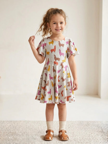 Young girl wearing a dress with llama pattern on a plain background
